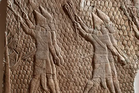 A stone relief carving of soldiers made in Assyria and now in the British Museum.