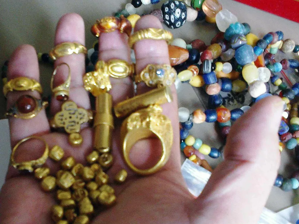 gold jewelry and beads held in a hand