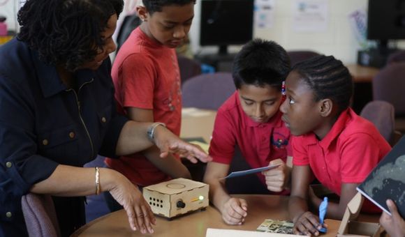 Teacher and three elementary students using Traveling Trunk content in the classroom