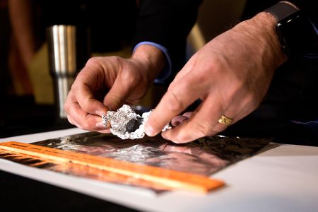 Astronomer Todd Slisher unfolds tin-foil to reveal a piece of stony-iron meteorite during a press conference, Friday, January 19, 2018, at the Longway Planetarium in Flint, Michigan.
