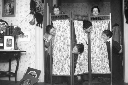 Wacky Victorian women play behind a clothing screen, ca. 1900.