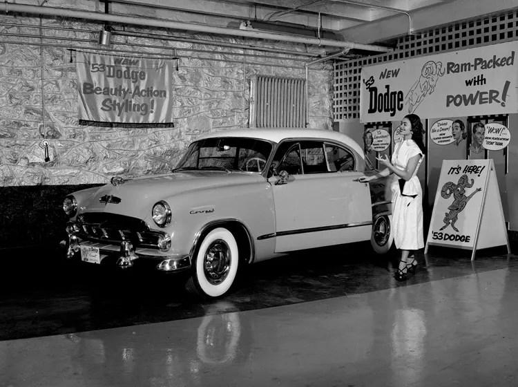 Woman gestures towards car in showroom