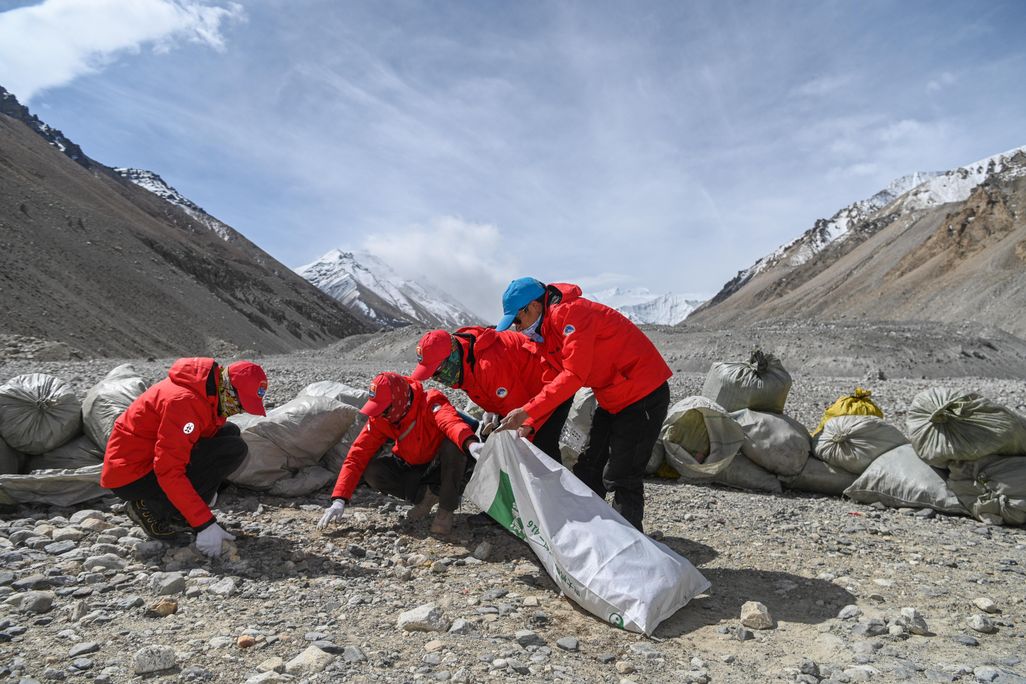 Men in red coats picking up trash