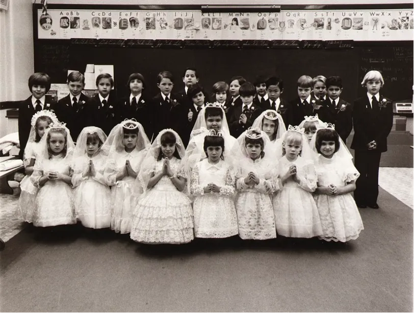 Black and white posed picture of a group of boys and girls in their first communion