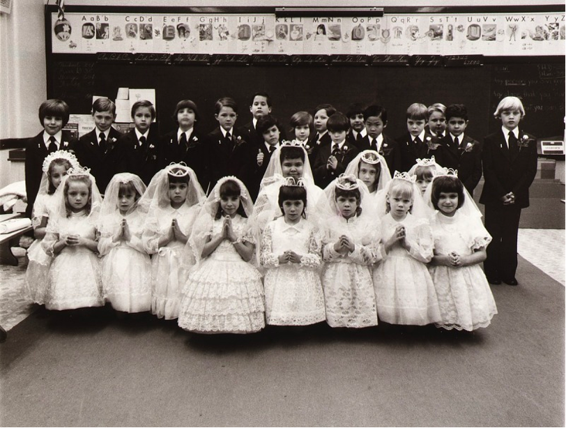 Black and white posed picture of a group of boys and girls in their first communion