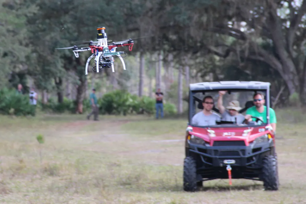 Drone outdoors trailed by researchers - credit Jonathan How, MIT.png