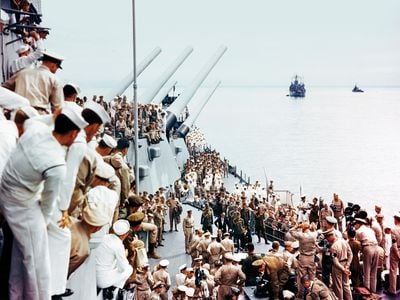 Sailors aboard the USS Missouri watch as dignitaries correct an error on the Japanese copy of the Instrument of Surrender. Many of the sailors had spent days cleaning and readying the ship for the pageant that 75 cameramen recorded for history.
