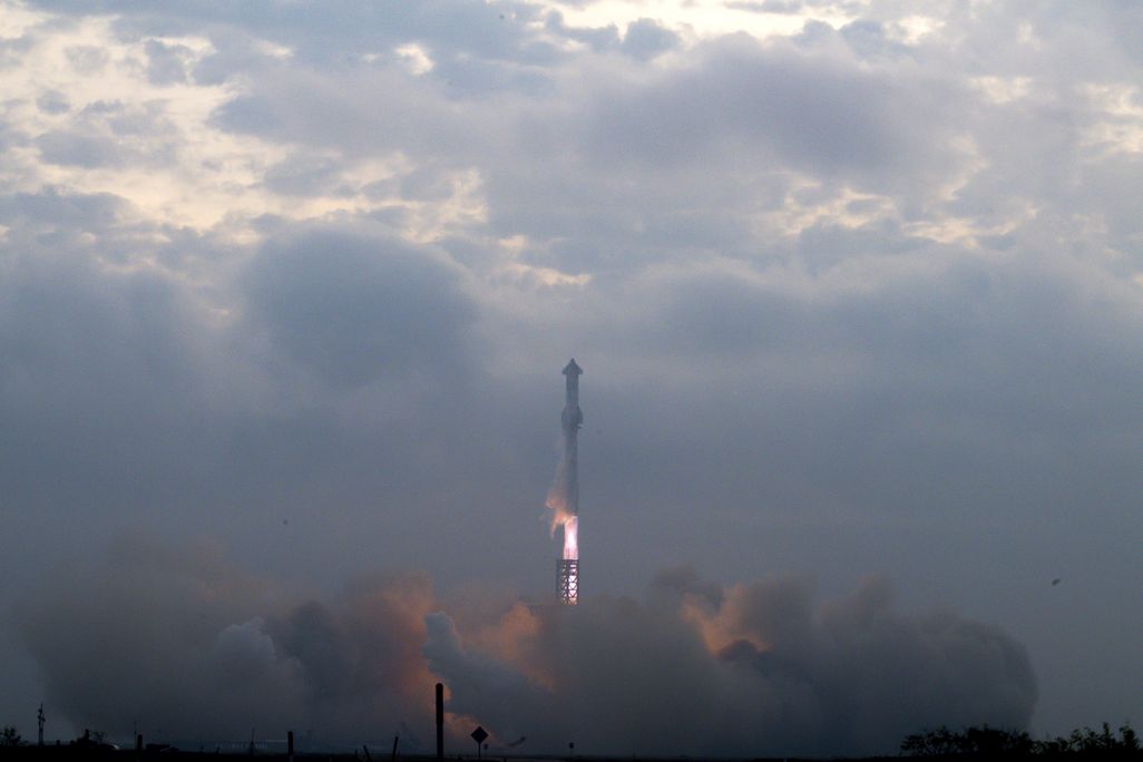 A rocket launching above a cloud of smoke into a cloudy sky