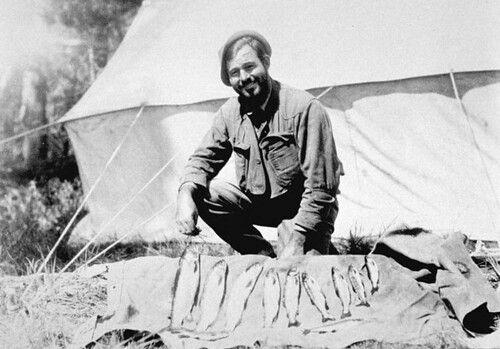 Ernest Hemingway poses for a photograph in front of a tent