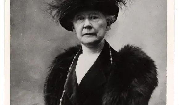 Black and white portrait of Mary Cassatt sitting in a chair wearing fur and a feathered hat.