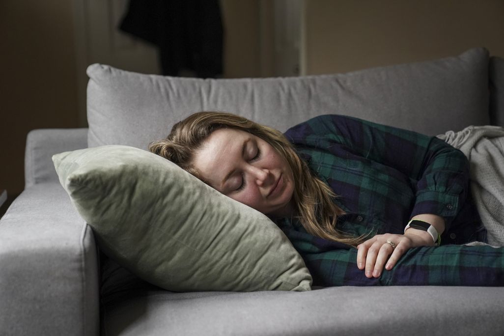a woman lies on her side on a couch, resting on a pillow