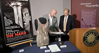Bruce Willis donates John McClane's undershirt to the National Museum of American History, as museum director Brent Glass looks on.
