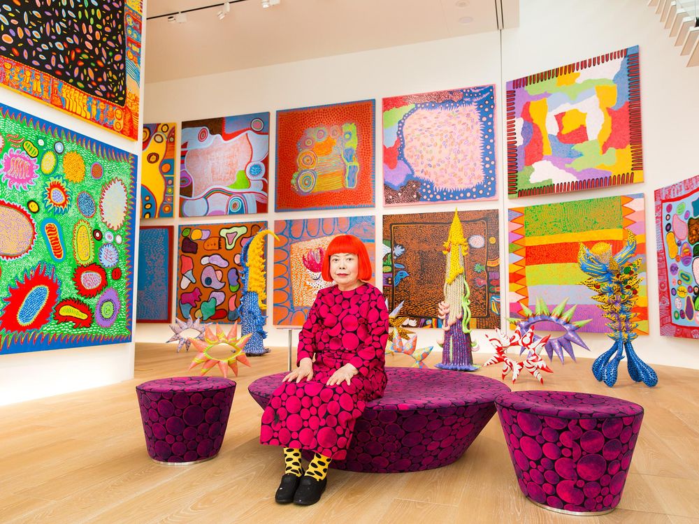 Women walk by the Pumpkin sculptures by Japanese artist Yayoi