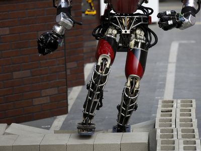 Team WPI-CMU’s robot climbs over cinder blocks during the finals of the DARPA Robotic Challenge
