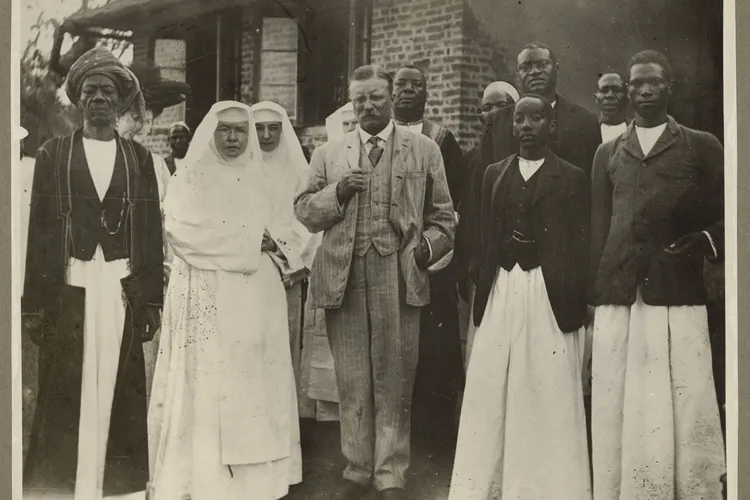 Roosevelt stands between the Sister of Rev. W.F. Bumsted, at that time mother superior of the convent, and the young King Daudi of Uganda, and is surrounded by members of the king&#39;s court at St. Mary&#39;s Convent, near Kampala, December 22, 1909