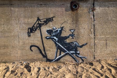 A vandal covered this mural of a rat sipping a cocktail in white spray paint.