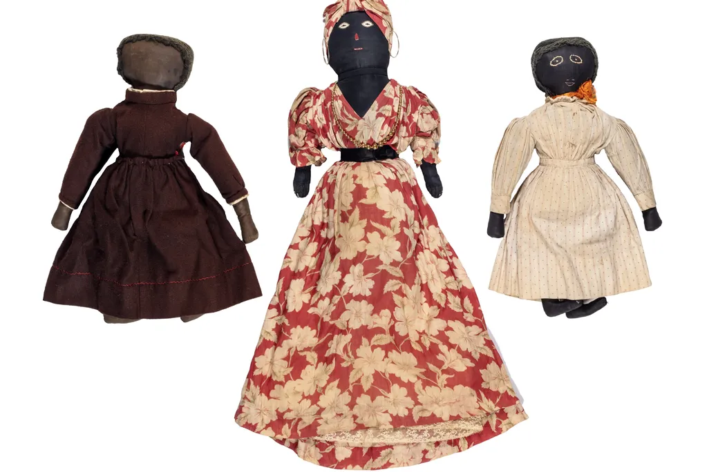 Three Black dolls of varying sizes with dresses made from dark red, patterned red flower and light pink fabrics