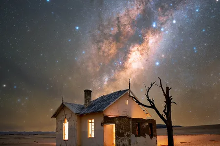An abandoned house in the Namib Desert with the Milky Way rising above it.