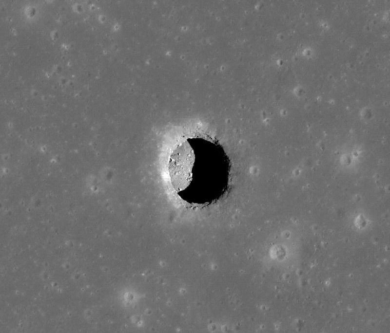 A grey image of a pit on the surface of the moon