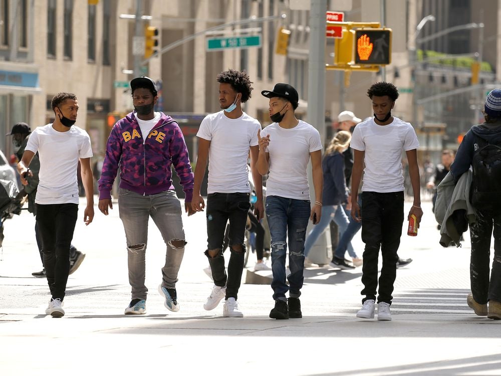 A group of men wearing protective masks walk in Midtown on April 10, 2021 in New York City.