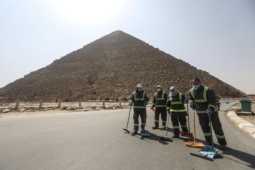 Workers stand in foreground with pyramid towering behind them