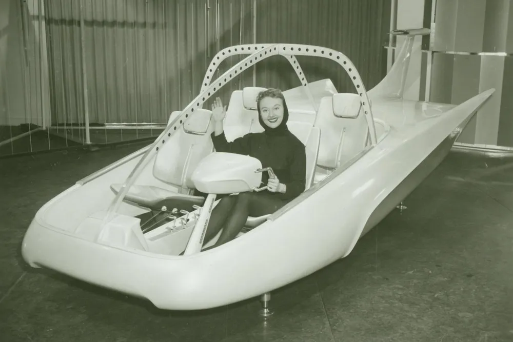 A woman poses in a full-scale model of the Studebaker-Packard Astral