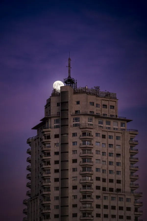 Full moon crowns a city tower at purple twilight thumbnail