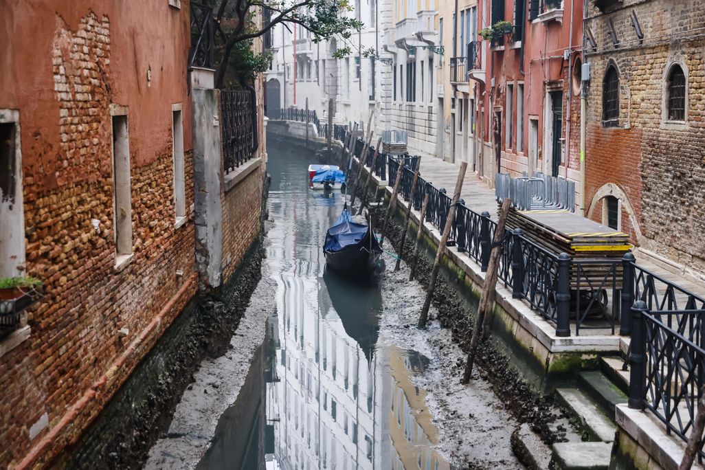 Boats in muddy canal with little water in Venice