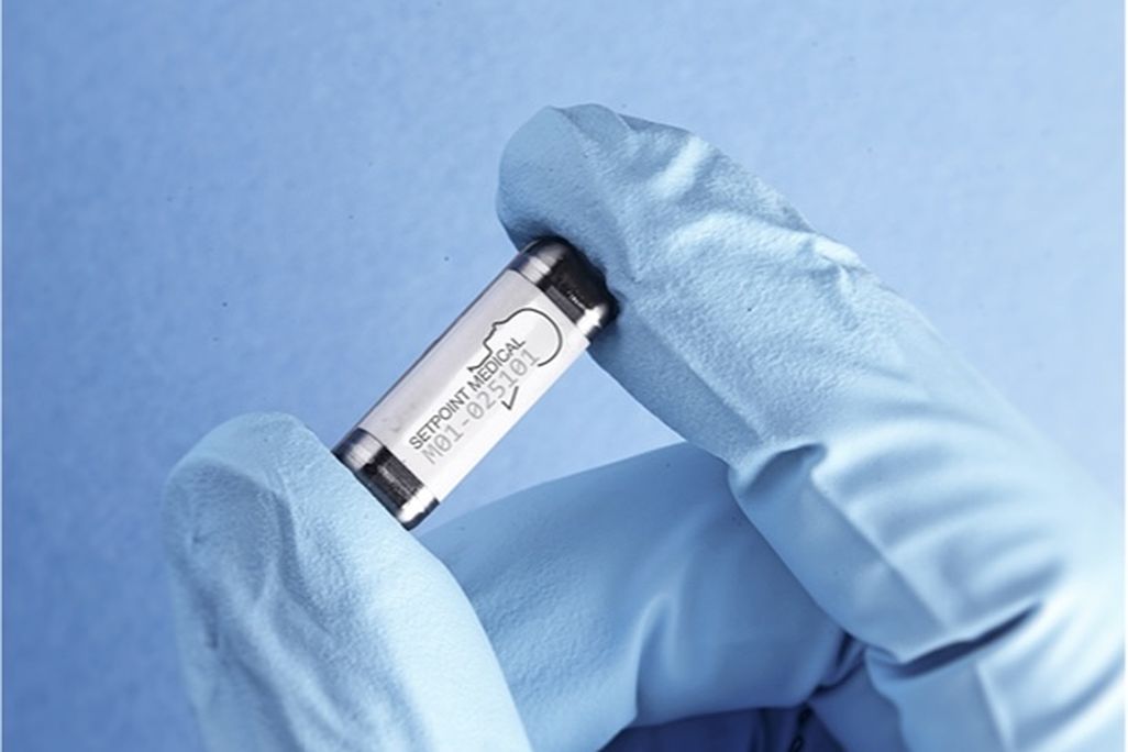 a blue gloved hand holds a pill-sized electronic capsule