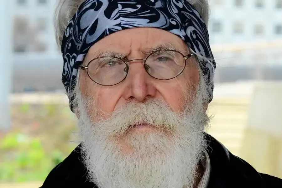 Close-up photograph of Michel Talagrand, who has a white mustache and beard and is looking at the camera and wearing a blue bandana and glasses.