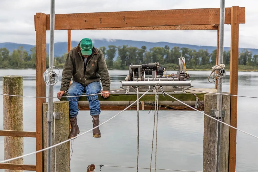 a man sits on wooden beams above a river