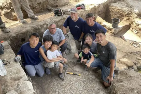 Archaeologists pose near the inscription found on the north shore of the Sea of Galilee