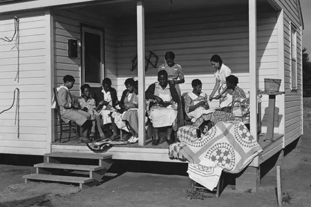 A group of women sewing a quilt on the porch of a property in Georgia, May 1939