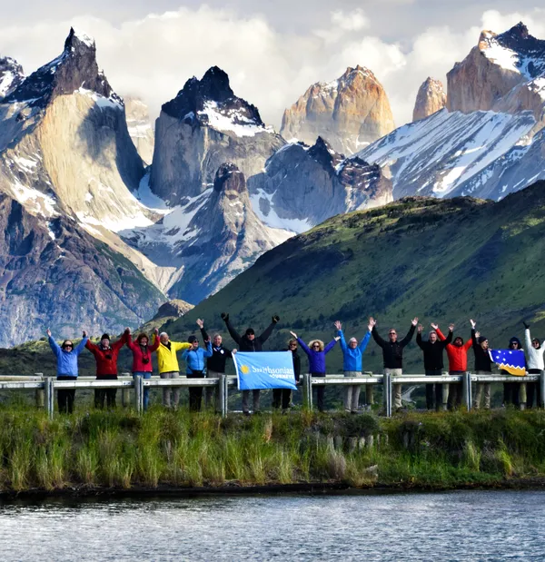 The Smithsonian Community (a Smithsonian Journeys travel group posing with raised arms together in Patagonia with mountains in the background)