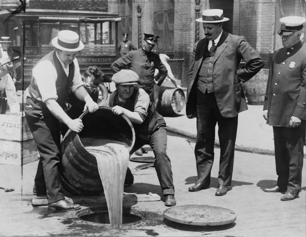 New York City Deputy Police Commissioner John A. Leach, right, watches agents pour liquor into a sewer following a raid at the height of Prohibition