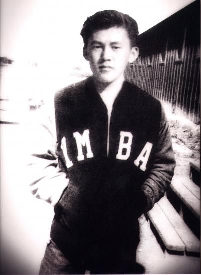 Black and white photo of Testuo Furukawa in YMBA letterman jacket