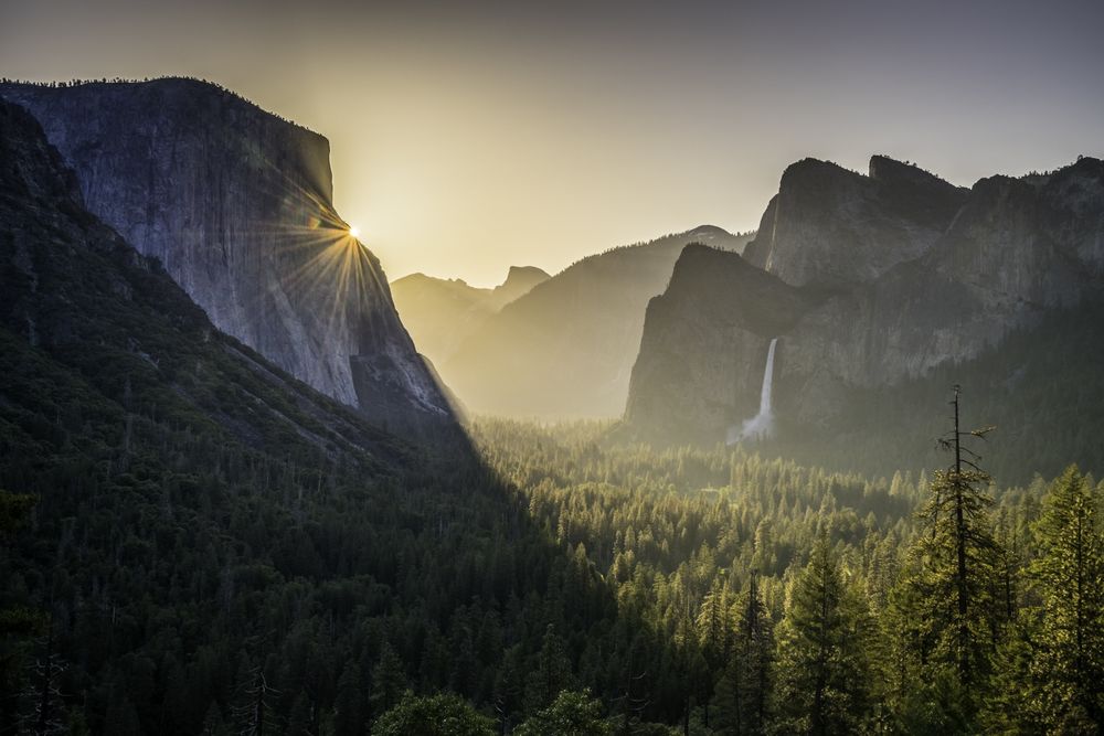 Sunrise at Tunnel View in Yosemite, NP. Made famous by Ansel Adams, catching the sunrise at Tunnel View is about as American as it gets in Yosemite National Park. The crowds arrive early (before 4 AM) to catch a spot along the wall. For at least ten minutes there is silence as the sun rises and sweeps across the valley. The only sound comes from fingers on the shutters.