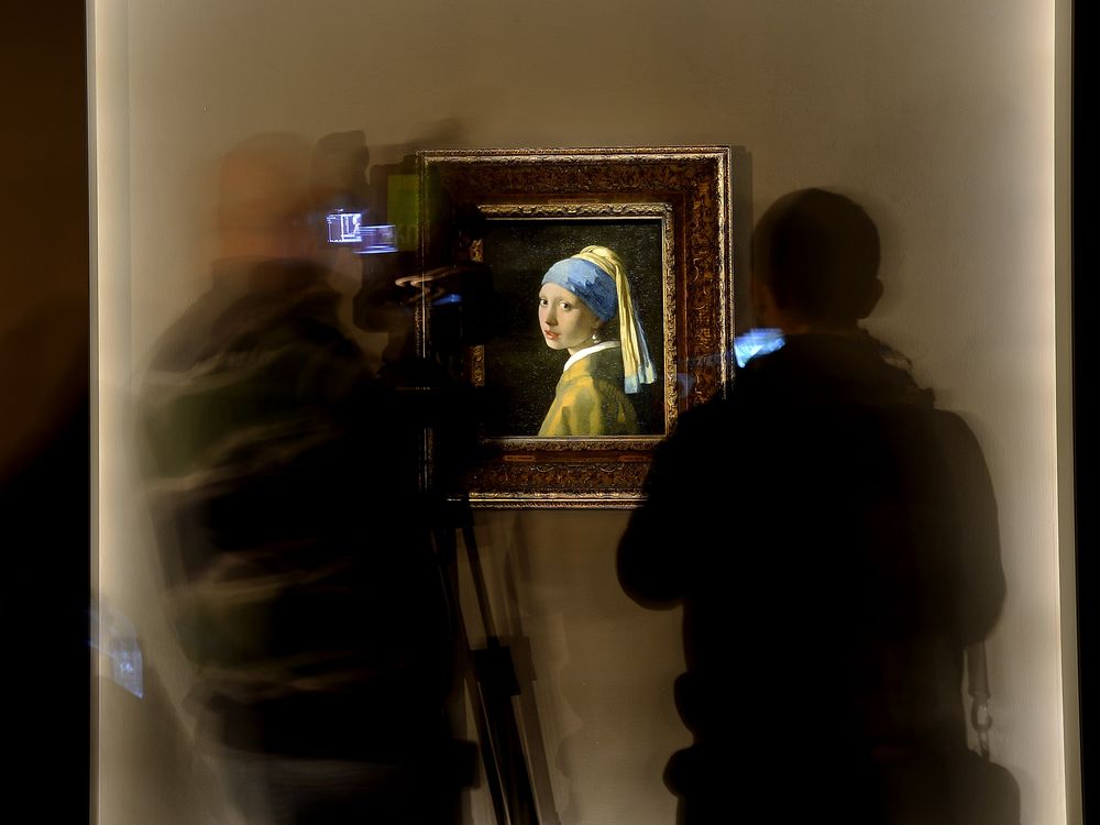 Journalists pass by the painting by Johannes Vermeer entitled Girl with a Pearl Earring