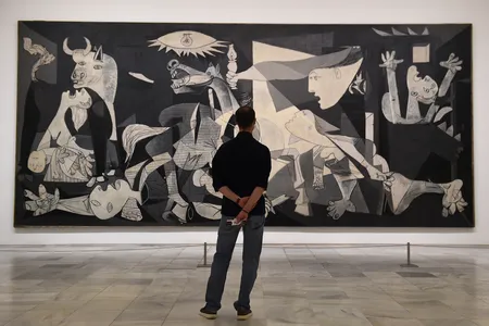 A visitor examines Pablo Picasso&#39;s Guernica during the partial reopening of the Reina Sof&iacute;a Museum in June 2020, which followed several months of pandemic closures.