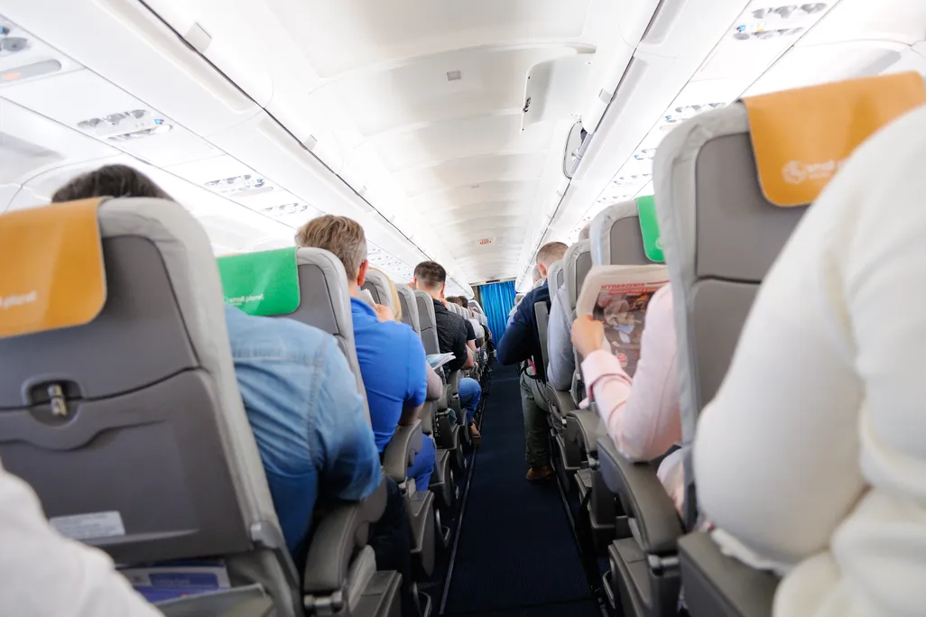 A photograph down the aisle of an airplane, from behind passengers