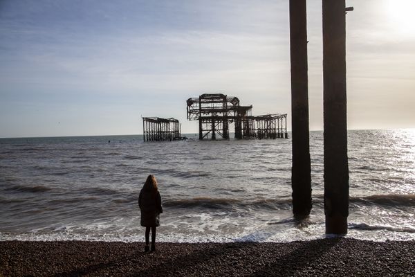 Young woman standing in front of the relic of an old pier. thumbnail