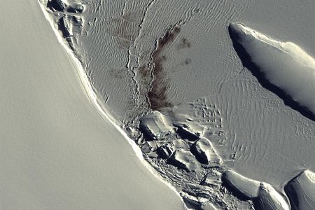 Against the pure white snow of Antarctica, an Emperor penguin colony appears in a QuickBird satellite image as a half-mile-long stain.