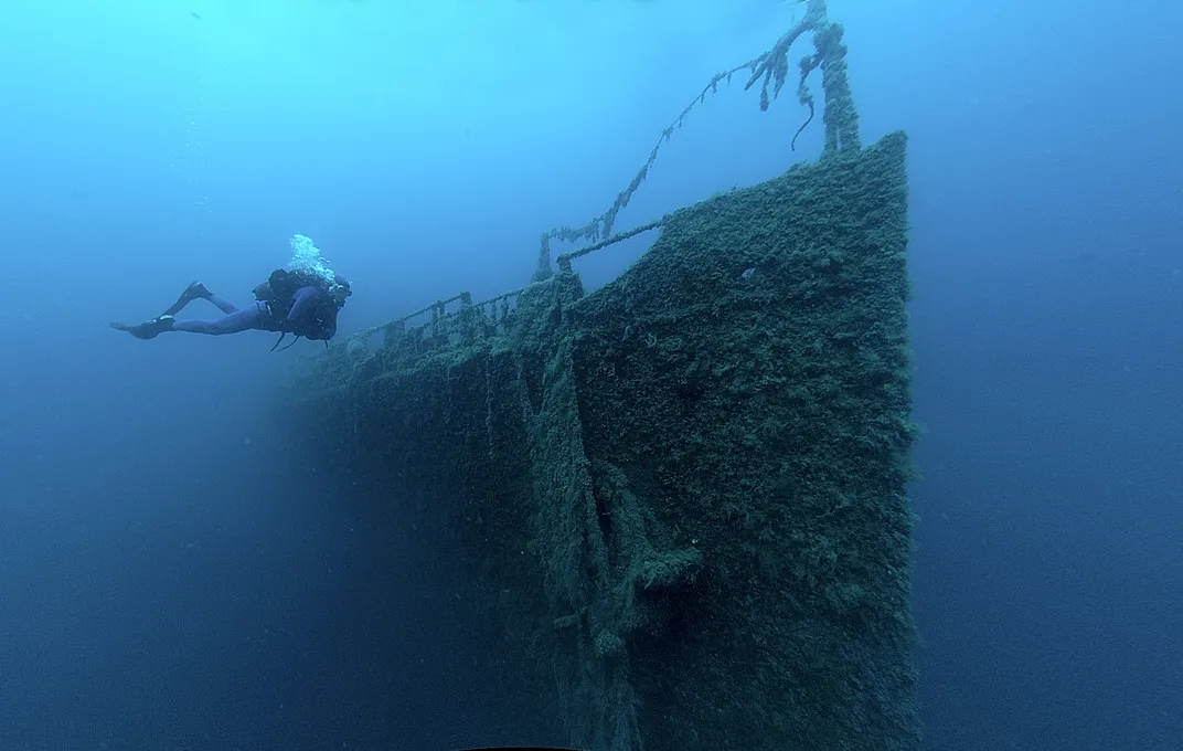 A diver next to part of a shipwreck under water