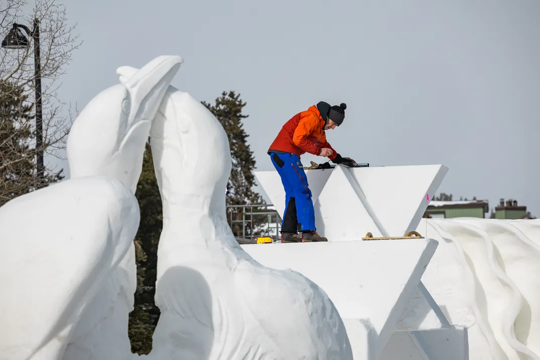 A man working on a snow sculpture