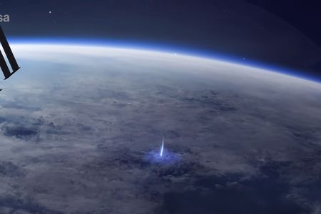 Artist's rendering of blue jet lightning blasting from a storm cloud towards space. The International Space Station solar panels can be seen in the foreground.