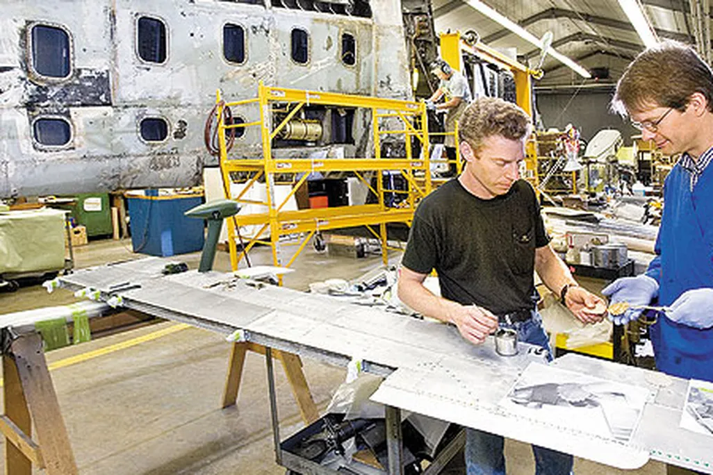 Whenever possible, original materials are saved. Project lead David Wilson (left) and chief conservator Malcolm Collum examine original fabric patches, used to cover bolt holes in the wing.