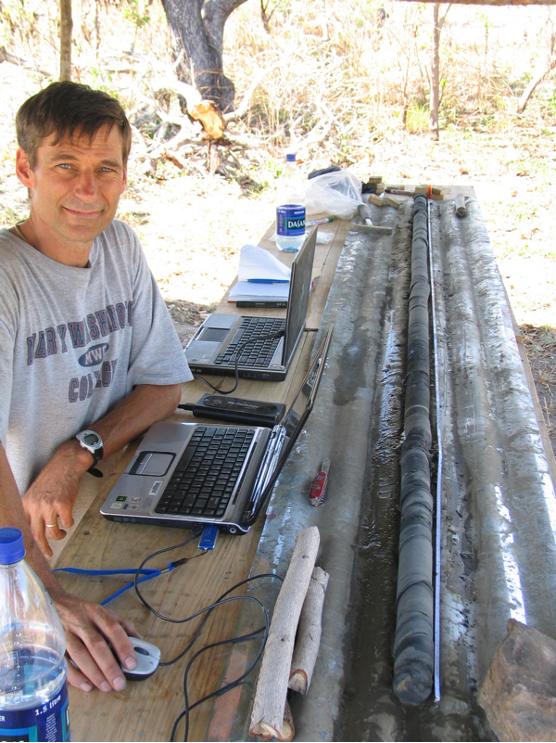 A person at a work bench with two laptops.