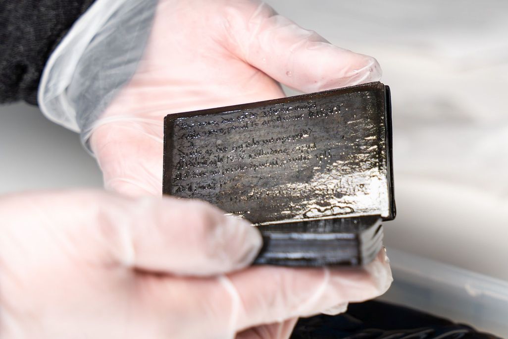 Conservator Susanne Bretzel holds the wax booklet up to the camera.