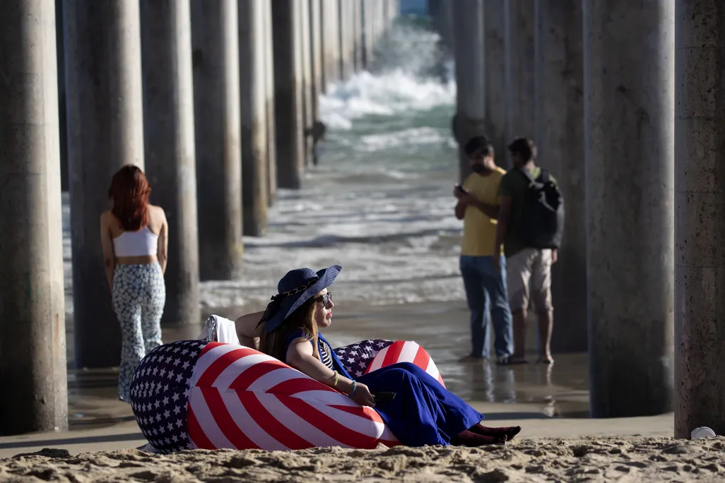 A person sitting in an American flag chair on the beach