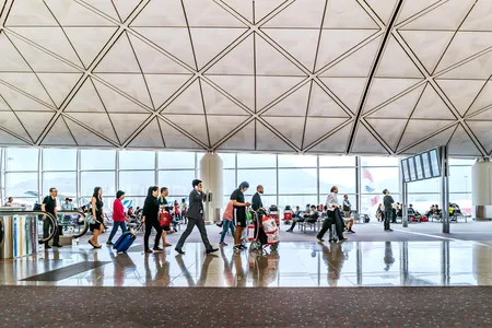 Travelers walk in the departure hall of Hong Kong International Airport.